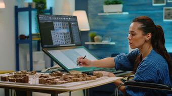 Une femme travaille sur une tablette avec à l'écran de son ordinateur, un outil de modélisation 3D