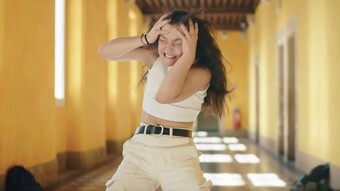 Capture du clip vidéo dans lequel une élève se tient la tête dans les mains dans un grand couloir vide